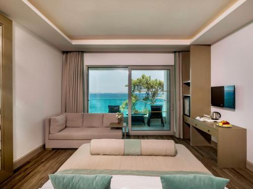 a living room with a couch and a large window at Blue Dreams Resort Bodrum - Aquapark & Ultra All Inclusive in Torba