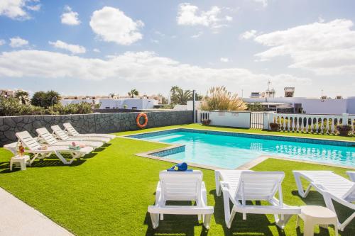 basen z białymi krzesłami i basen w obiekcie Beautiful 2 Bed Villa with large pool Casa Manana w mieście Playa Blanca