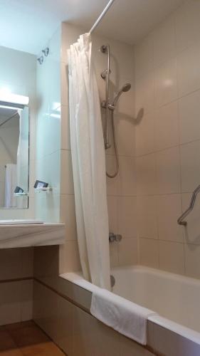 a bathroom with a tub and a shower with a shower curtain at Apartamentos Baños de Ledesma in Salamanca