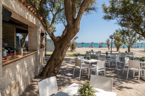 a restaurant with tables and chairs next to the beach at Caldera Creta Paradise in Plataniás