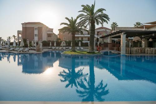 a large swimming pool with palm trees and buildings at Caldera Creta Paradise in Platanias