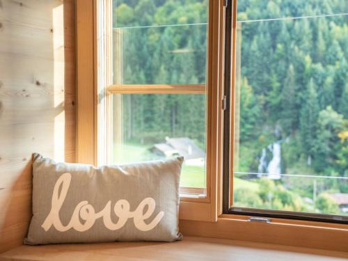 a pillow with the word love sitting in front of a window at Hotel Wasserfall in Jaun