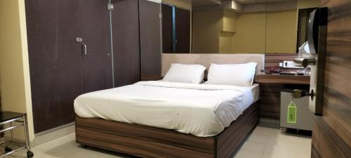 a bedroom with a large bed with white sheets at Hotel Lucky Galaxy in Mumbai