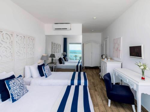 a hotel room with two beds and a desk at Blue Dreams Resort Bodrum - Aquapark & Ultra All Inclusive in Torba