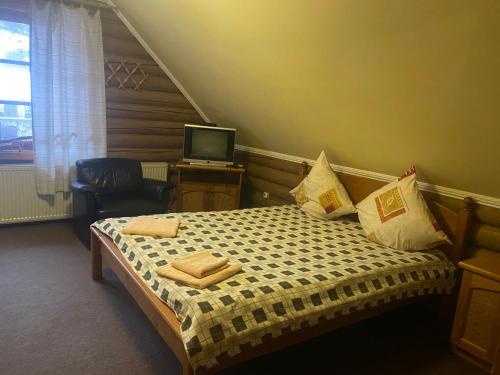 a bedroom with a bed with pillows and a television at Verkhovinsky Dvor in Kostryna