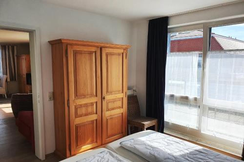 sypialnia z drewnianą szafką obok okna w obiekcie Dünenblick Wohnung 47 w mieście Boltenhagen