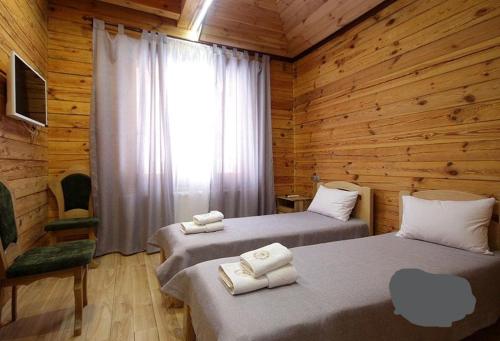 Duas camas num quarto com paredes de madeira e uma janela em Golden Nest em Yablunytsya
