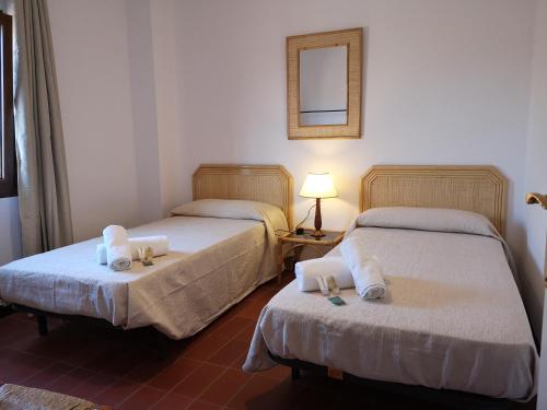 two beds in a room with a lamp and a mirror at La Rajoleria para desconectar. Lloguer 30. in Llagostera