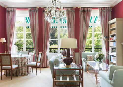 a living room with red curtains and a chandelier at Brenners Park Hotel & Spa, Oetker Hotels in Baden-Baden