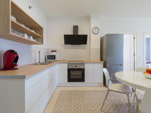 a kitchen with white cabinets and a table and a refrigerator at FIRST LINE MOGAN BEACH - Parking free in Mogán