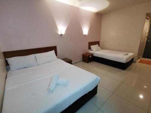 ein Hotelzimmer mit 2 Betten mit weißer Bettwäsche in der Unterkunft Sweet Star Hotel in Alor Setar