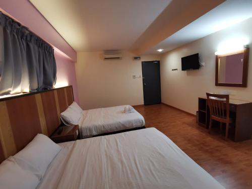 a hotel room with two beds and a television at Sweet Star Hotel in Alor Setar