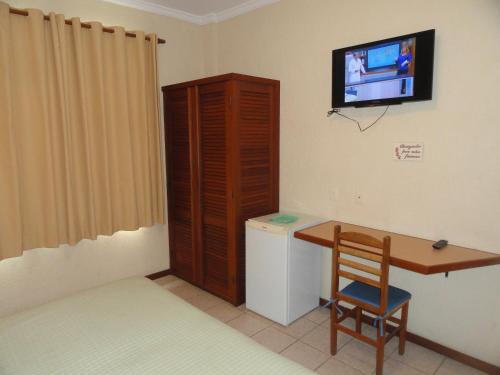 a room with a desk and a television on a wall at Village du Soleil in Cabo Frio