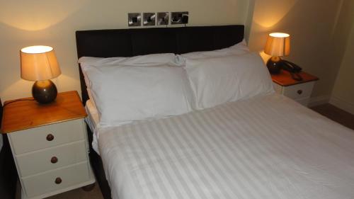 a bedroom with a white bed with two lamps on night stands at Hannon's Hotel in Roscommon
