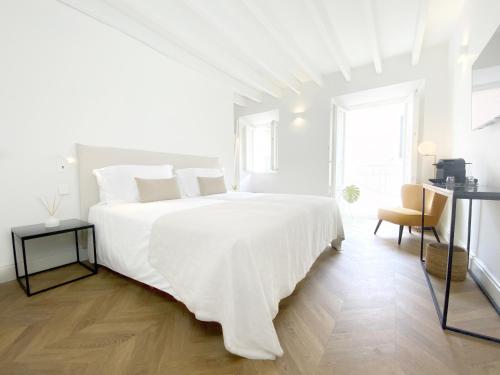 a white bedroom with a large white bed and a chair at Son Melt Esporles in Esporlas