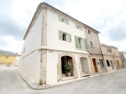 a white building with green shutters on a street at Son Melt Esporles in Esporlas