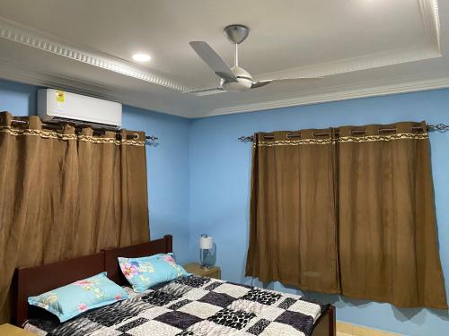 1 dormitorio con paredes azules y ventilador de techo en Brand New 3-Bed House in Oyibi Accra Ghana, en Oyibi