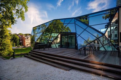 a glass building with a table on a deck at Apart Hotel Jablonec in Jablonec nad Nisou