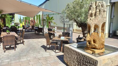 a fountain in the middle of a patio with tables and chairs at Hotel Speeter in Weisenheim am Berg