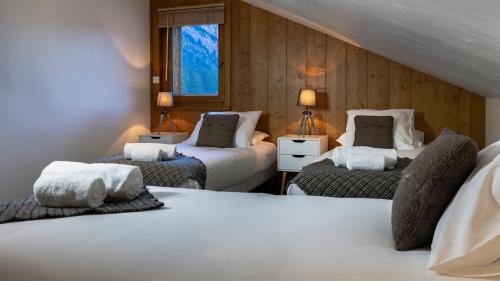 een slaapkamer met 2 bedden, 2 lampen en een raam bij La Snaille des Planards in Chamonix-Mont-Blanc