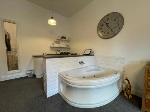 uma casa de banho com banheira e um relógio na parede em The Townhouse Boutique Hotel em Barrow in Furness
