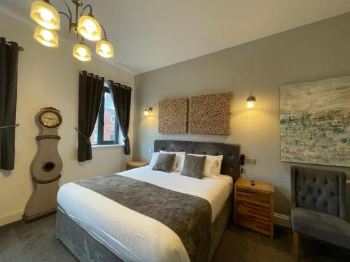 um quarto com uma cama e um relógio na parede em The Townhouse Boutique Hotel em Barrow in Furness
