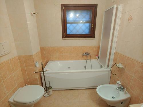 a bathroom with a tub and a toilet and a sink at Nonna Genoveffa, camere in Infernetto