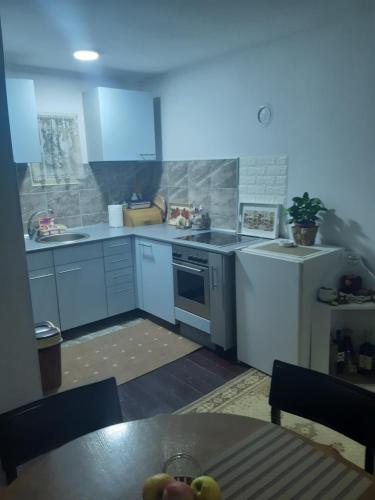 a kitchen with white appliances and a table with fruit at Seosko turističko domaćinstvo Stojković in Aleksinac