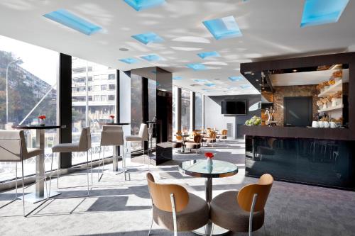 a hotel lobby with chairs and tables and a bar at Melia Barcelona Sarriá in Barcelona