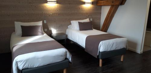two beds sitting next to each other in a room at Logis Hôtel "Ici m'aime" in Rouvray