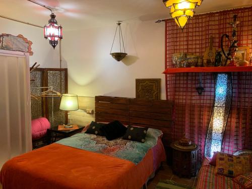 Schlafzimmer mit einem Bett mit orangefarbener Bettwäsche und Beleuchtung in der Unterkunft La Casa del Pianista in Monachil