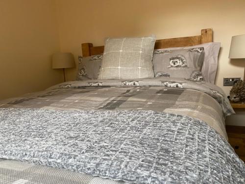 uma cama com um cobertor e almofadas azuis e cinzentos em Ye Old Tack Room em Stafford