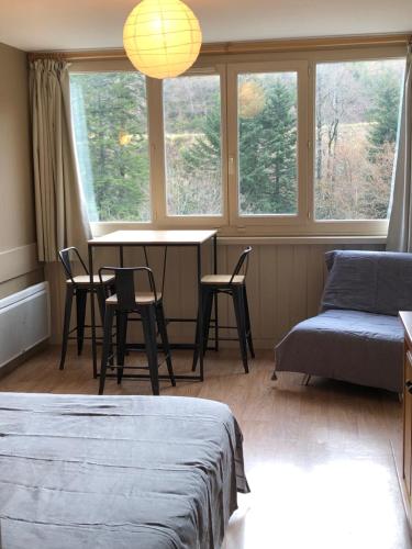 a room with a table and chairs and windows at La Randonnée Résidence Le Bec de L'Aigle in Le Lioran