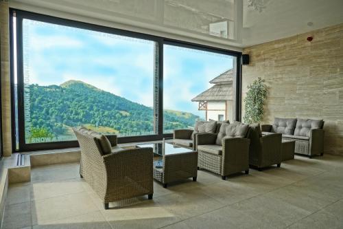 a living room with chairs and a table and large windows at Apart & Spa Zoned in Kopaonik