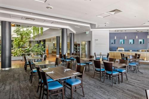 a restaurant with tables and chairs and a bar at Novotel Darwin CBD in Darwin