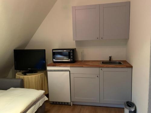 eine kleine Küche mit einer Mikrowelle und einem TV auf der Theke in der Unterkunft Gästehaus Höpkens Ruh in Bremen