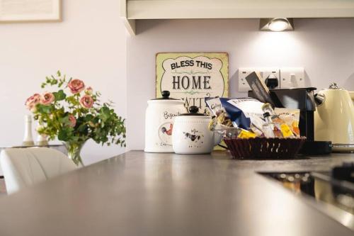 a kitchen counter with flowers and a sign that reads bless this home at The Cedars, Cromer, a 7.5 minute walk to the beach in Cromer
