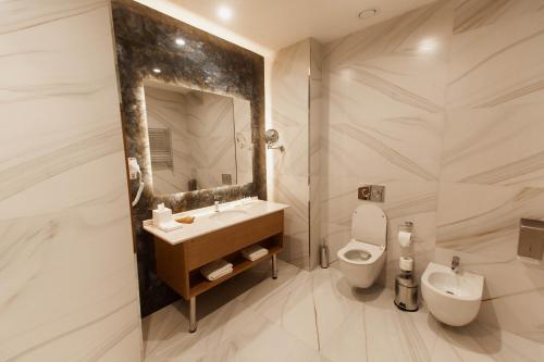 a bathroom with a sink and a toilet and a mirror at Farovon Khiva Hotel in Khiva