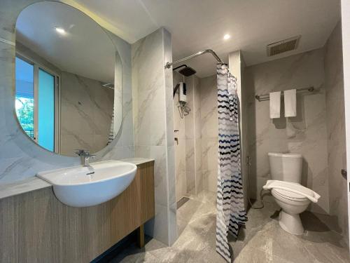 La salle de bains est pourvue d'un lavabo, d'un miroir et de toilettes. dans l'établissement The Corner มุมม่วน คาเฟ่ แอนด์ โฮสเทล MumMuan hostel, à Chiang Mai