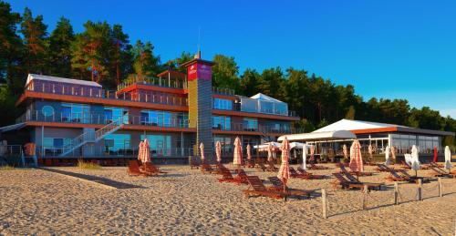 un hotel sulla spiaggia con sedie e ombrelloni di Boutique Hotel Light House Jurmala a Jūrmala