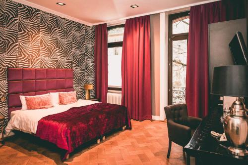 Hotel Villa Klemm - Wiesbaden City في فيسبادن: غرفة نوم بسرير وستائر حمراء ونافذة