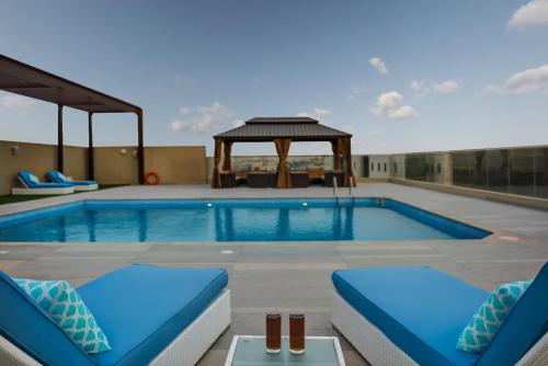 a swimming pool with chairs and a gazebo at ABAR HOTEL APARTMENTS DIP-1 in Dubai