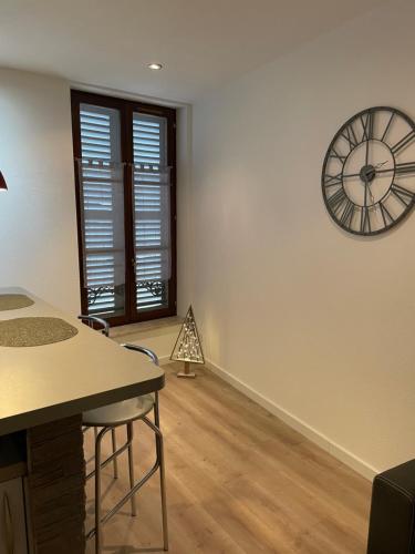 une chambre avec une horloge sur le mur et une table dans l'établissement Chaleureux F2 dans l’hypercentre colmarien, à Colmar