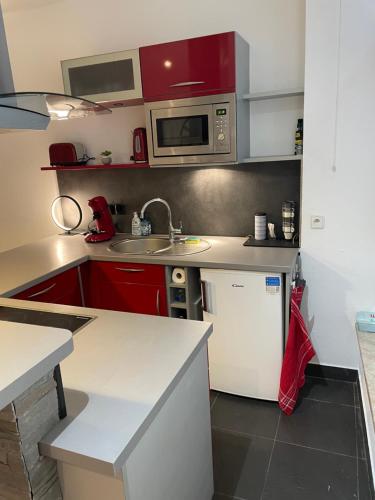 une cuisine avec des armoires rouges et un réfrigérateur blanc dans l'établissement Chaleureux F2 dans l’hypercentre colmarien, à Colmar