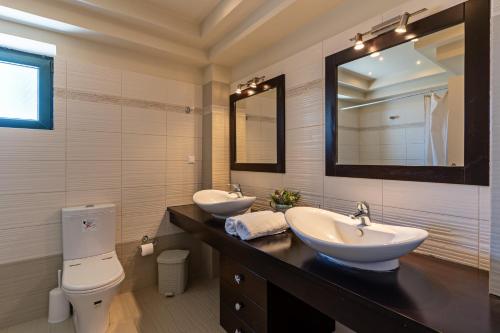 a bathroom with two sinks and a toilet and a mirror at The Artemis Home, pure rustic romance, By ThinkVilla in Astérion