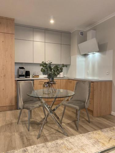uma cozinha com uma mesa de vidro e 2 cadeiras em Ultra Apartments Kamienica Nova em Szczecin