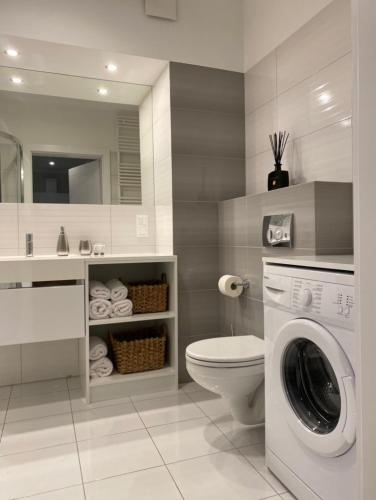 a bathroom with a washing machine and a toilet at Ultra Apartments Kamienica Nova in Szczecin