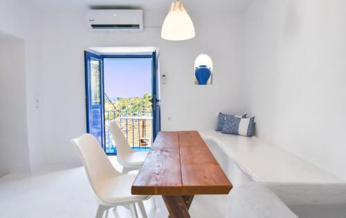 comedor con mesa de madera y sillas blancas en The Blue and White house in Ioulis, Kea en Kéa