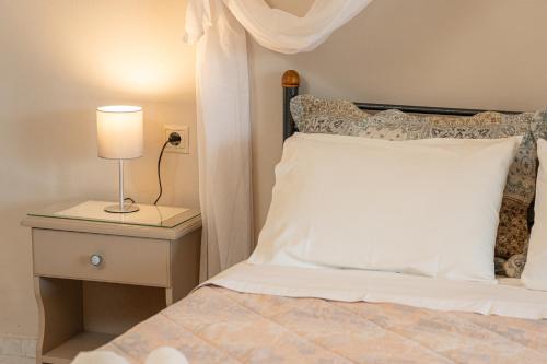 a bed with a white pillow and a lamp on a night stand at Minas Apartments in Divarata