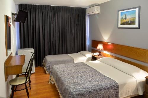 a hotel room with two beds and a television at Hotel Hispano in Montevideo